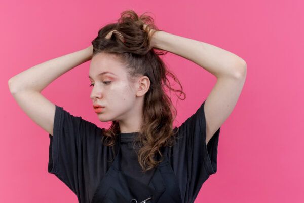 Una giovane ragazza posa su uno sfondo rosa tenendosi i capelli con entrambe le mani - Cos’è la miniaturizzazione?