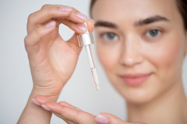 Ragazza che tiene in mano un contagocce con dell'olio. L'olio di ricino è un buon alleato per i capelli.