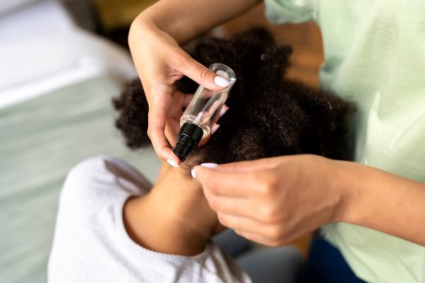 Ragazza che applica il siero sulla testa di una ragazza