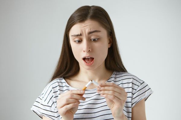 Ragazza sorpresa perché la sigaretta è rotta. Smettere di fumare può essere più difficile di quanto pensiamo