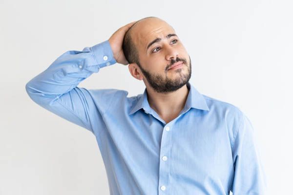 uomo calvo che pensa mentre si tocca la testa - Trapianto Capelli a Roma prezzi